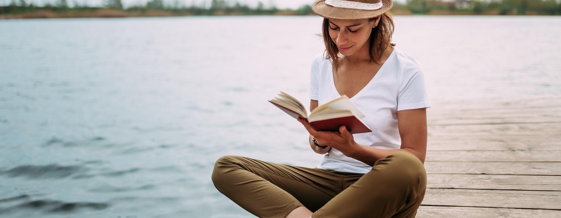 a person sitting on a dock reading a book